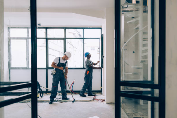 Two colleagues doing construction work together in an unfinished building.